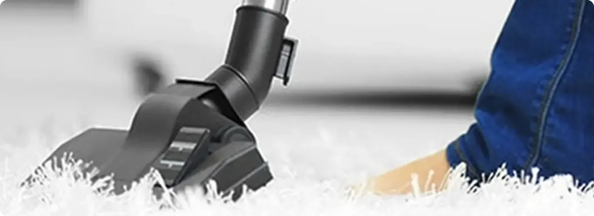 Close-up of a professional vacuuming a white carpet in Prairie Village.